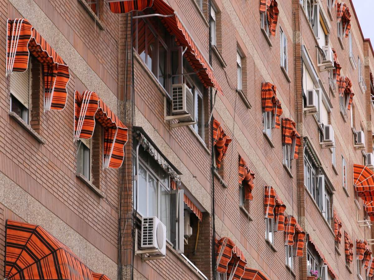 Fachada de ladrillo con ventanas y toldos en un bloque de viviendas