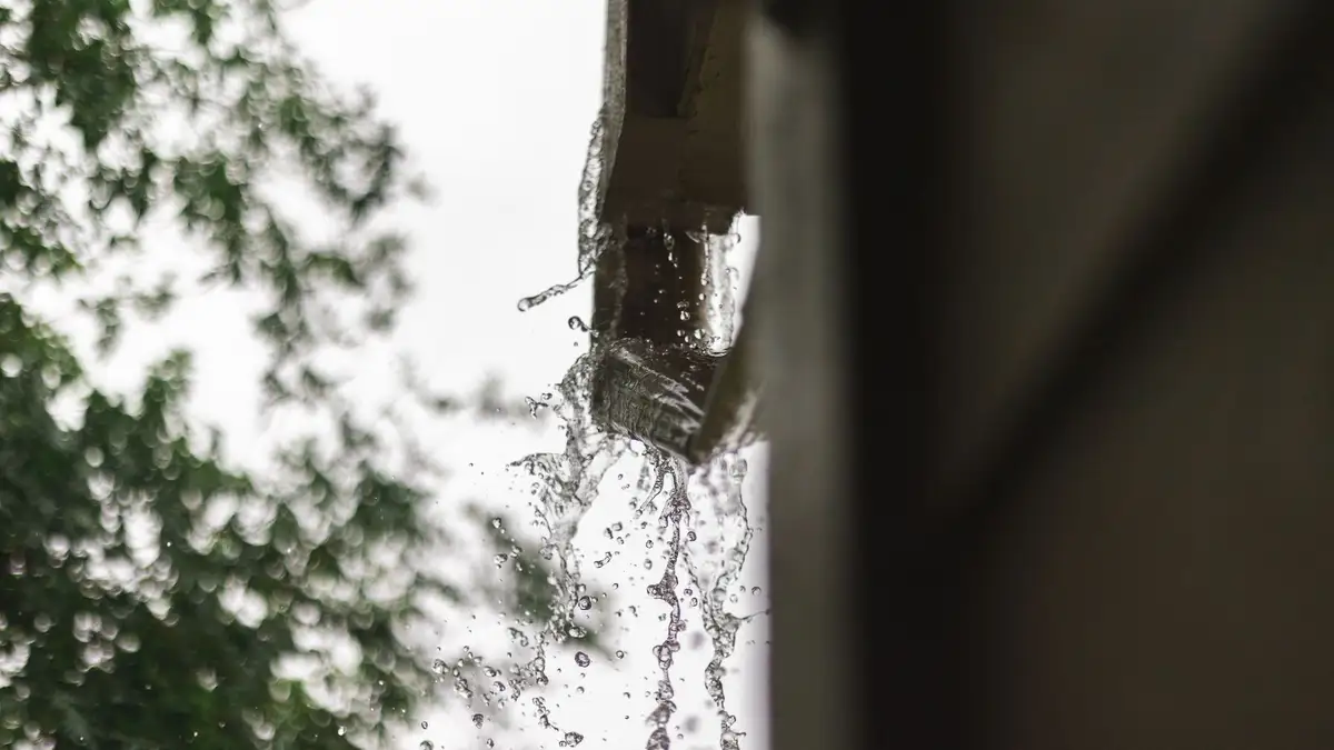 Agua de lluvia cayendo por el borde de un canalón