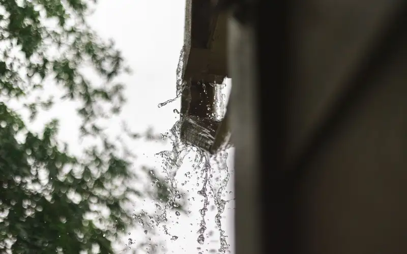 Agua de lluvia cayendo por el borde de un canalón