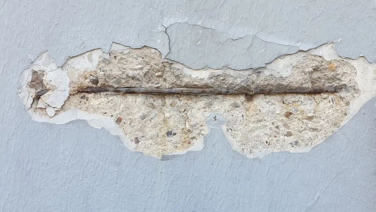 Detalle de un muro con el revestimiento desprendido y una armadura metálica a la vista
