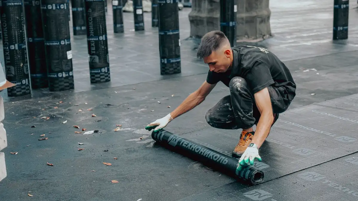 Técnico aplicando una lámina impermeable sobre una cubierta plana