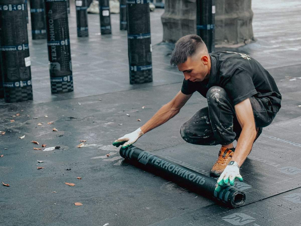 Operario extendiendo una lámina impermeabilizante sobre una cubierta plana