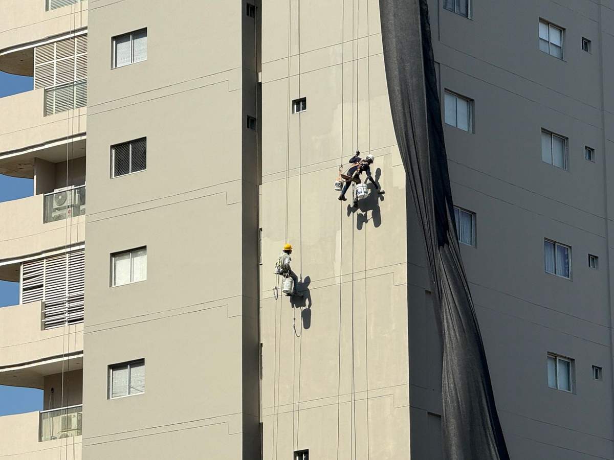Dos técnicos de trabajos verticales descolgándose por la fachada de un edificio
