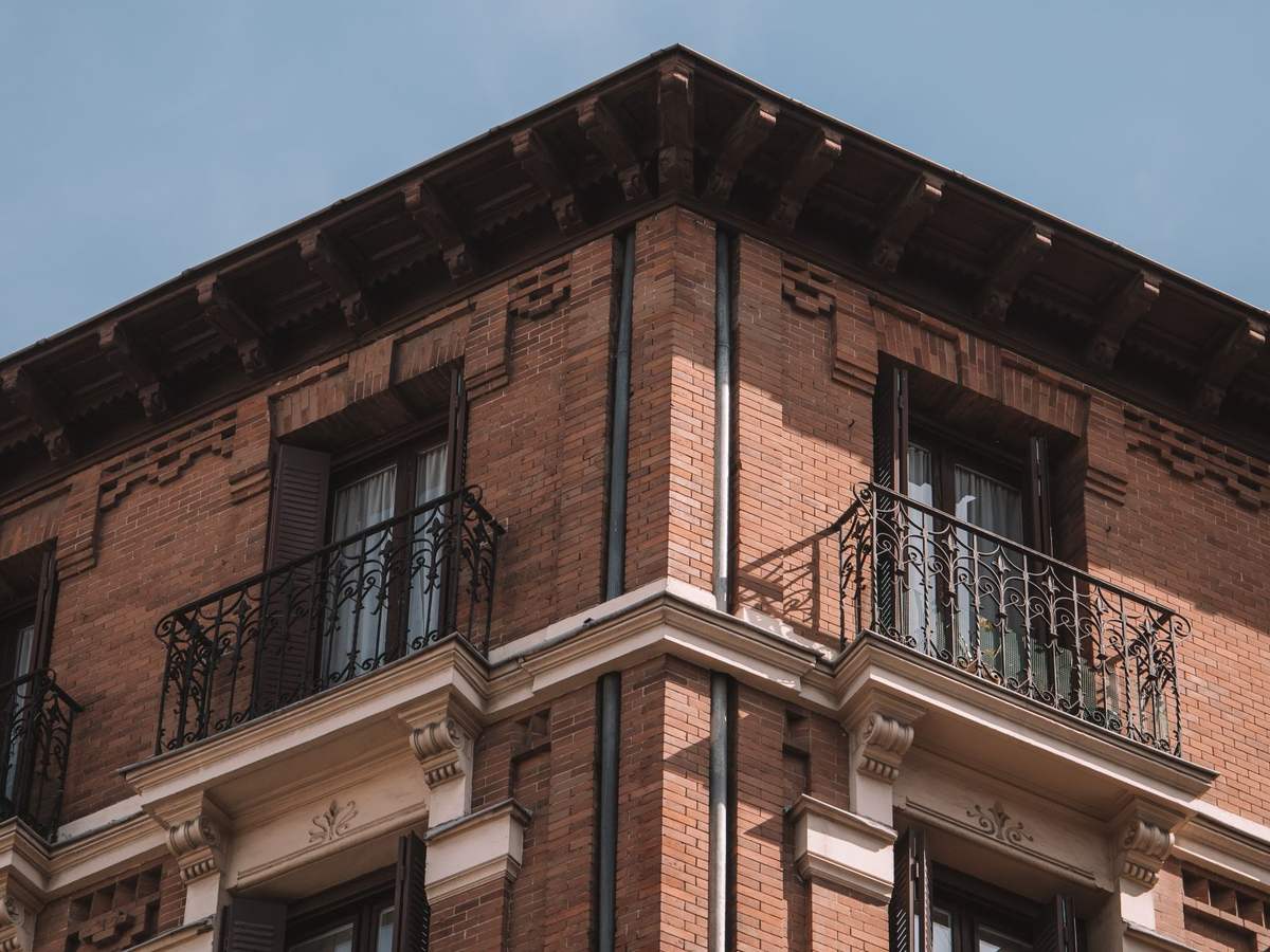 Edificio residencial de ladrillo rojo con balcones visto desde abajo