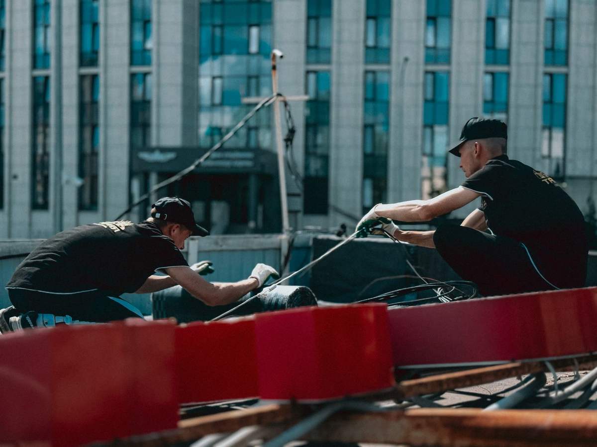 Dos operarios realizando trabajos de mantenimiento en la cubierta de un edificio urbano