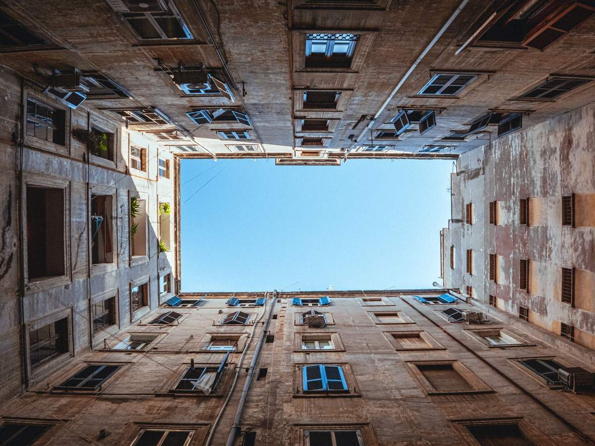 Patio interior de un bloque de viviendas visto desde abajo, con el cielo despejado