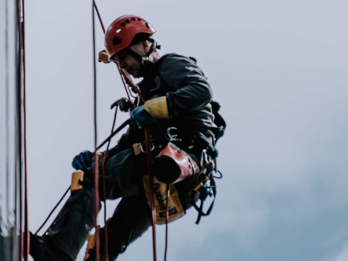 Técnico de trabajos verticales con casco descendiendo por una fachada