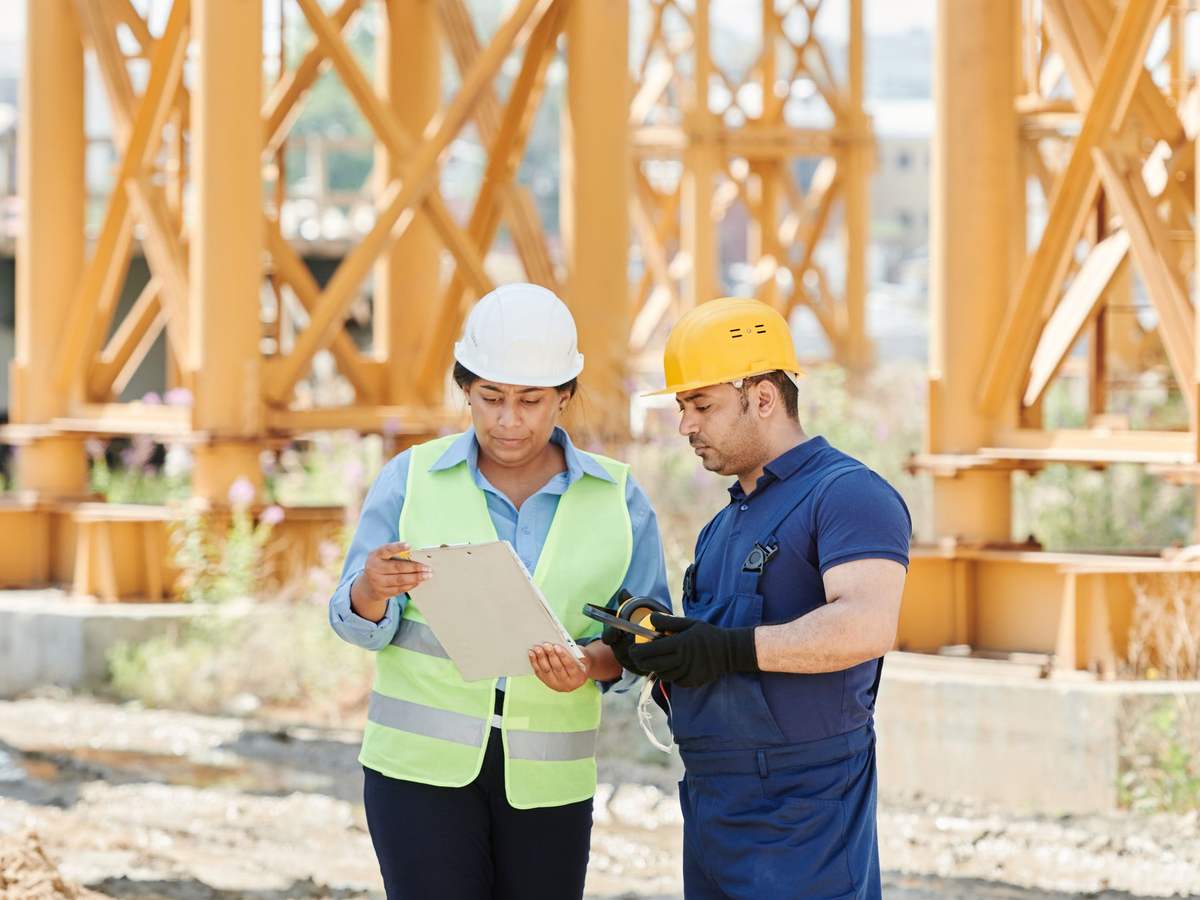 Dos técnicos de trabajos verticales revisando los planos de un edificio antes de una obra